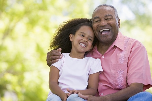 Grandfather laughing with granddaughter outside after restoring vision with cataract surgery