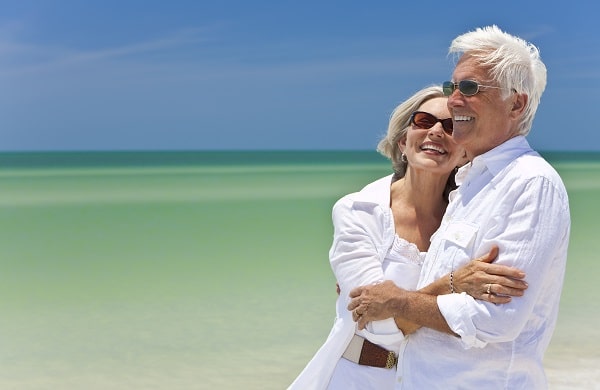 Senior couple at the beach wearing sunglasses to protect their eyes