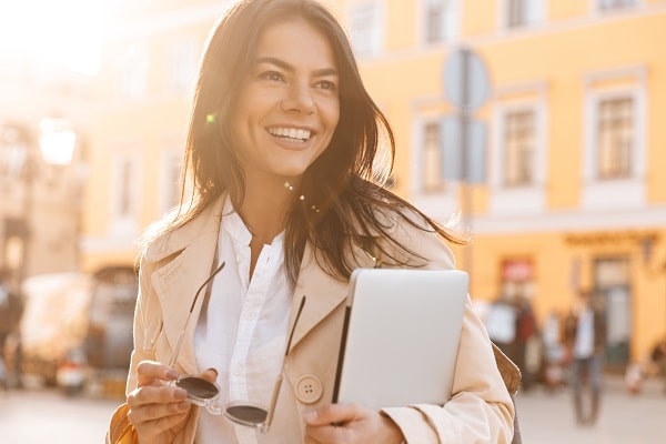 Woman smiling and holding her sunglasses with clear vision after LASIK