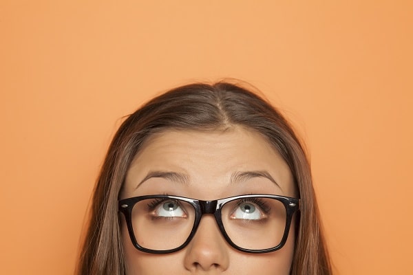 Close up of young woman looking upward and wearing glasses