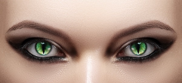 Closeup of a woman's eyes with green cat-style Halloween lenses